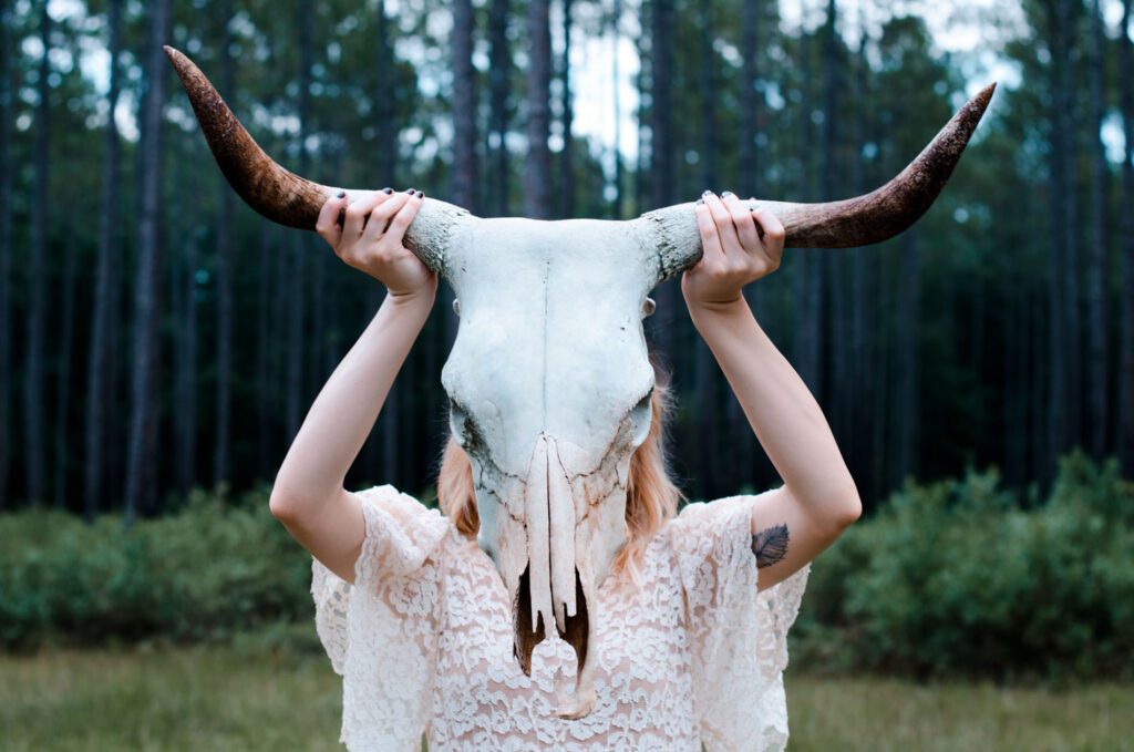A woman holding up two horns on her head.