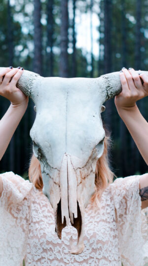 A woman holding up two horns on her head.