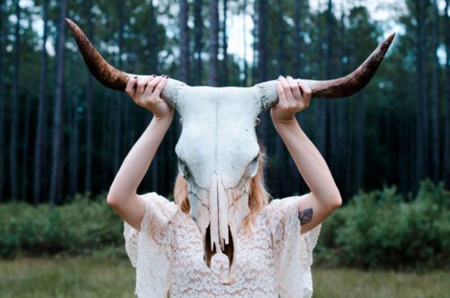 A woman holding up two horns on her head.