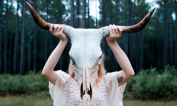 A woman holding up two horns on her head.