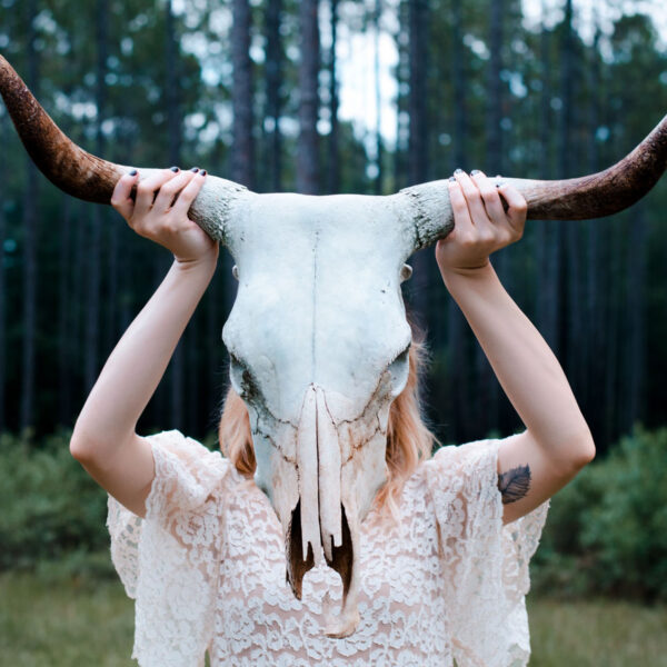 A woman holding up two horns on her head.
