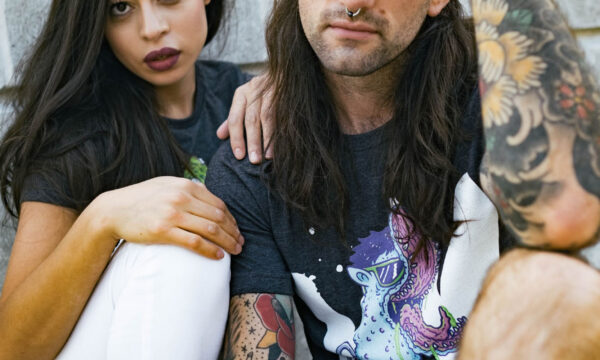 A man and woman sitting on the ground with tattoos.