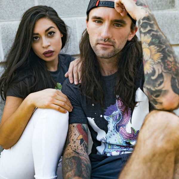 A man and woman sitting on the ground with tattoos.