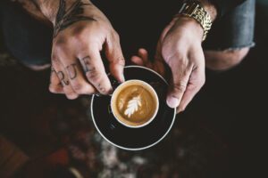 A person holding a cup of coffee on top of a saucer.