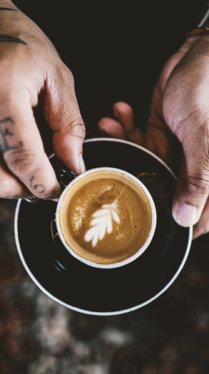 A person holding a cup of coffee on top of a saucer.