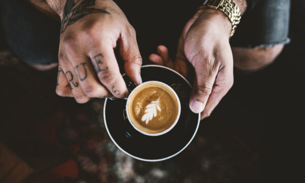 A person holding a cup of coffee on top of a saucer.