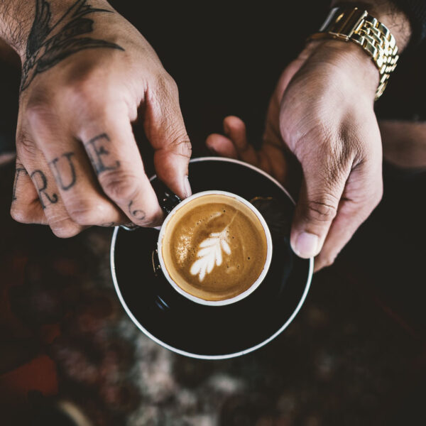 A person holding a cup of coffee on top of a saucer.