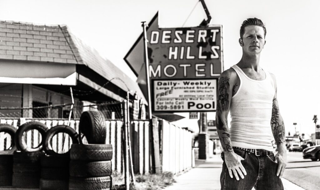 A man standing in front of a motel sign.