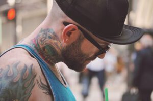 A man with tattoos and glasses on his face.