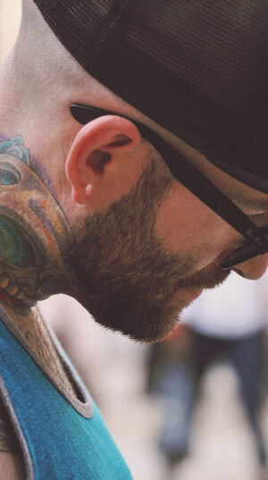 A man with tattoos and glasses on his face.