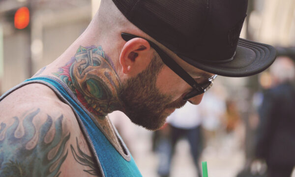 A man with tattoos and glasses on his face.