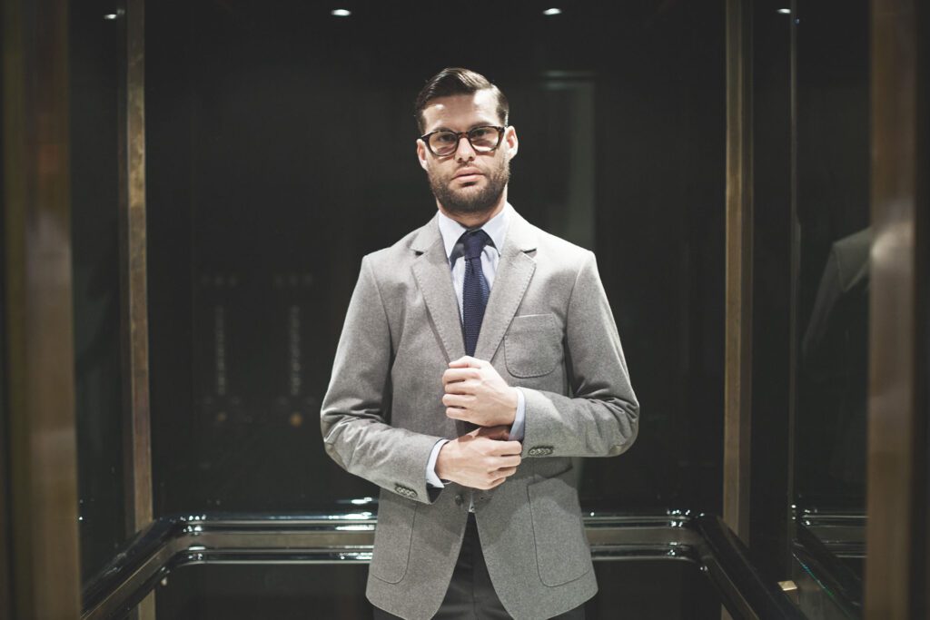 A man in suit and tie standing next to glass.
