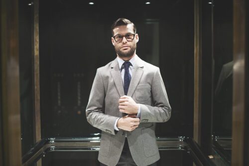 A man in suit and tie standing next to glass.