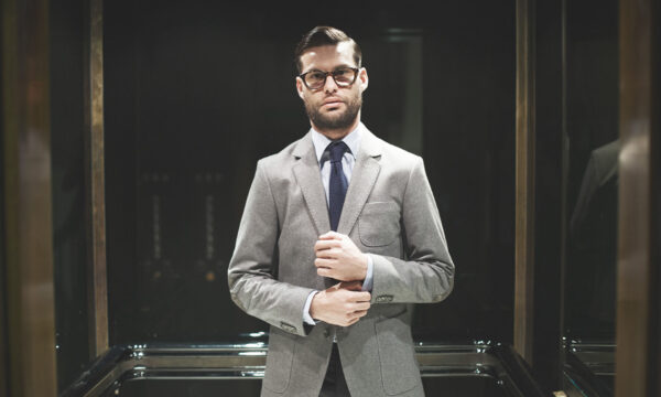 A man in suit and tie standing next to glass.