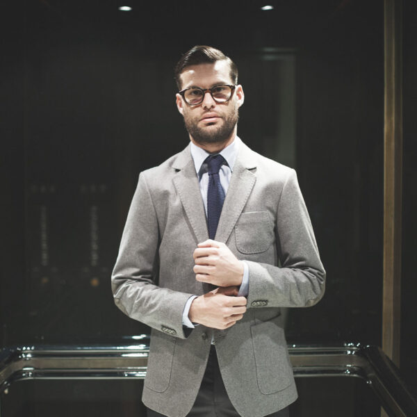 A man in suit and tie standing next to glass.