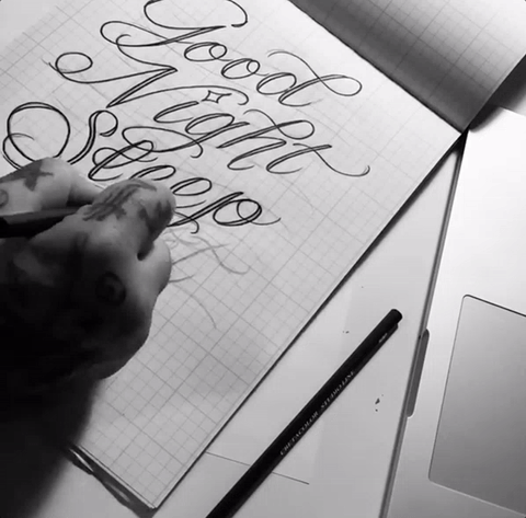 A person writing on paper with a pencil.
