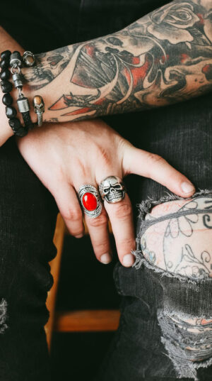 A person with tattoos and rings on their hands.