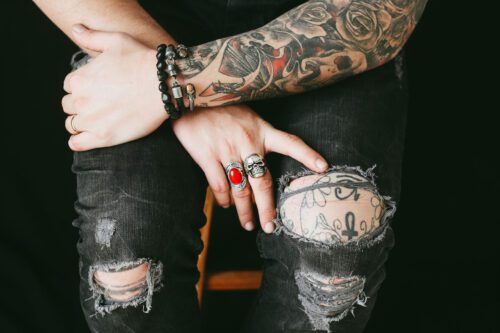 A person with tattoos and rings on their hands.