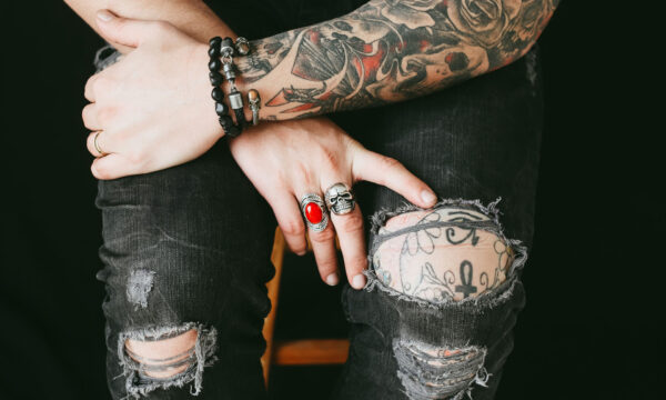 A person with tattoos and rings on their hands.