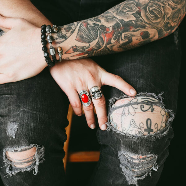 A person with tattoos and rings on their hands.
