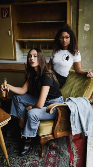 Two women sitting in a chair with one holding a knife.