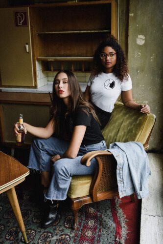 Two women sitting in a chair with one holding a knife.