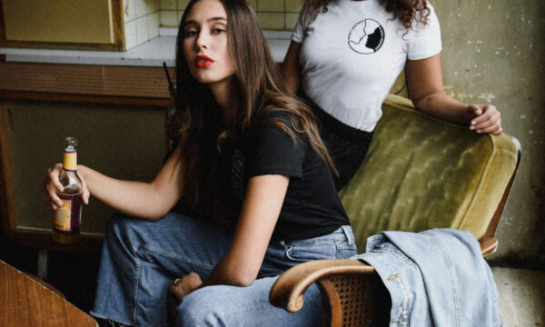 Two women sitting in a chair with one holding a knife.