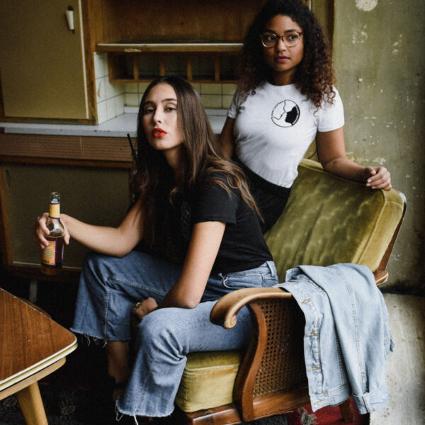 Two women sitting in a chair with one holding a knife.