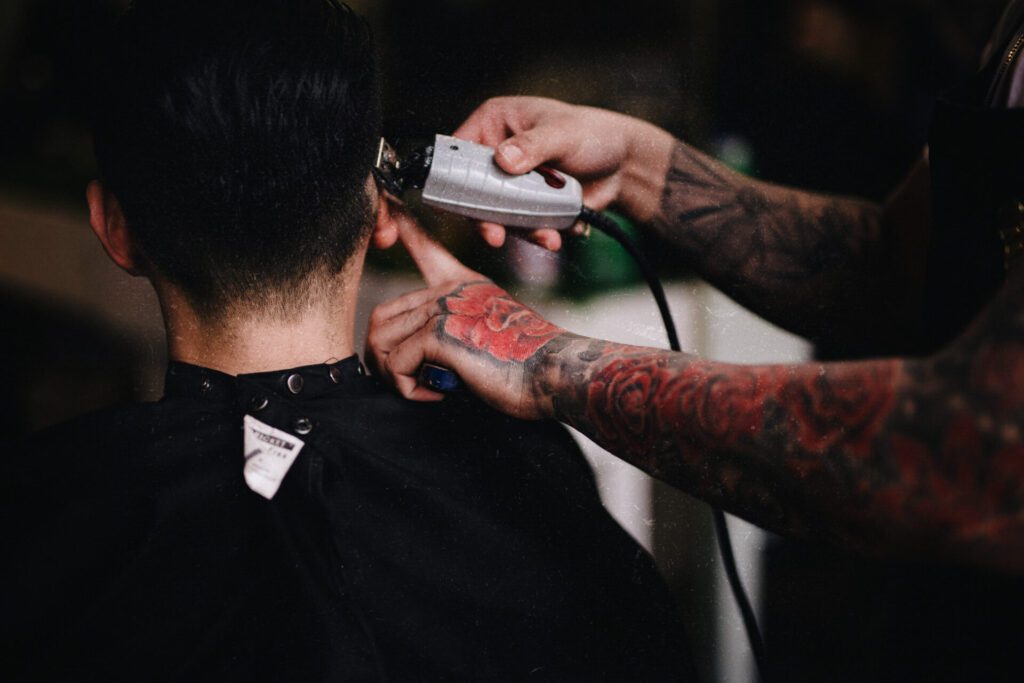 A man getting his hair cut by another person.