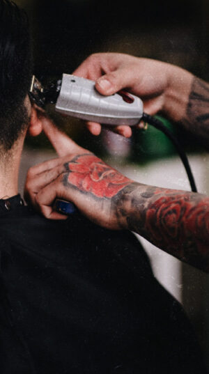 A man getting his hair cut by another person.