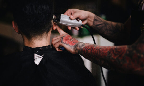 A man getting his hair cut by another person.