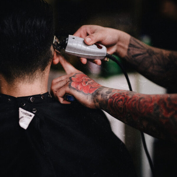 A man getting his hair cut by another person.