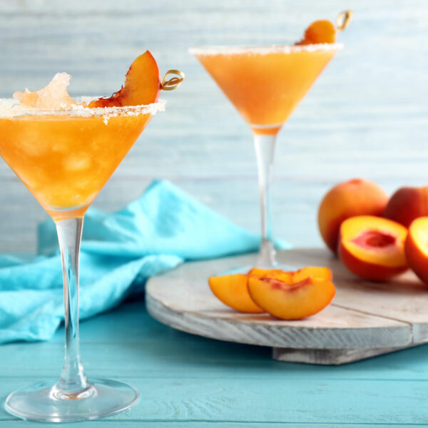 Two glasses of peach and orange juice on a table.